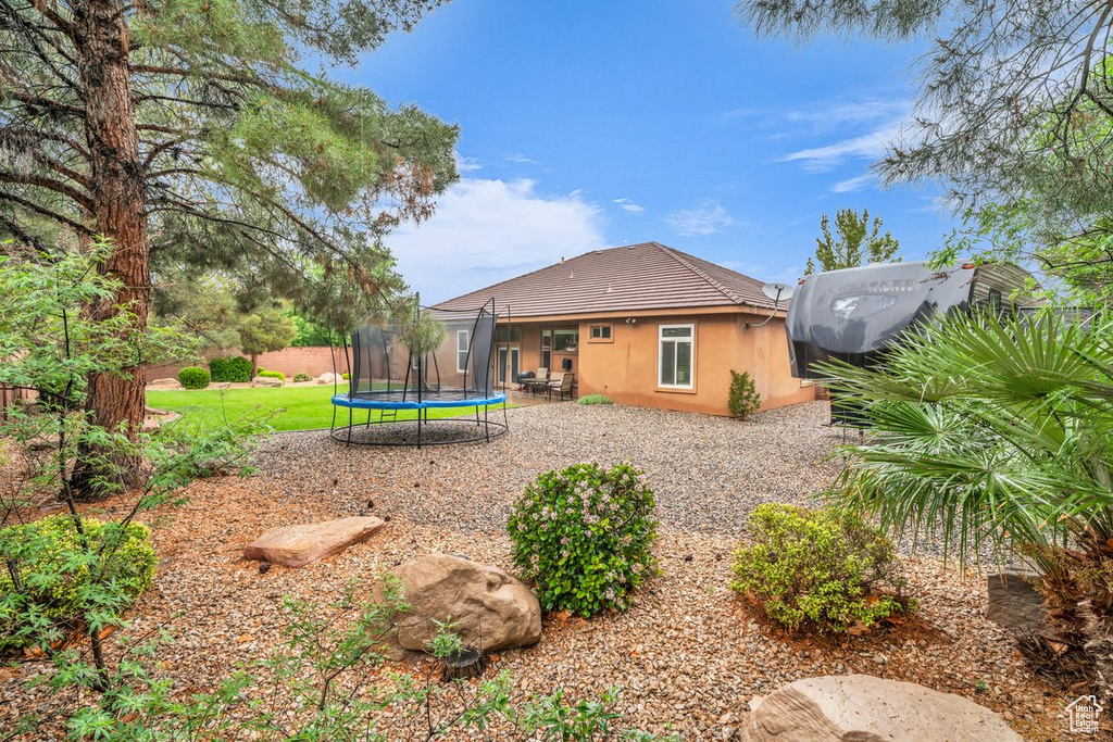 Back of house featuring a trampoline, stucco siding, a tile roof, and a patio