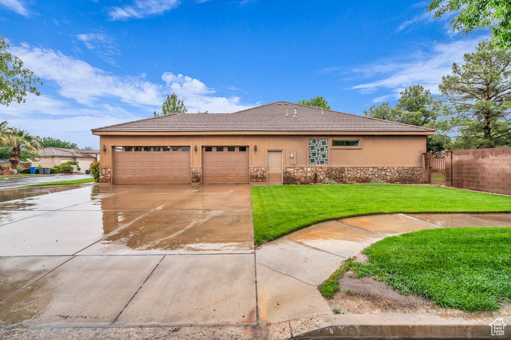 View of front of house featuring stone siding, concrete driveway, stucco siding, a tile roof, and a garage
