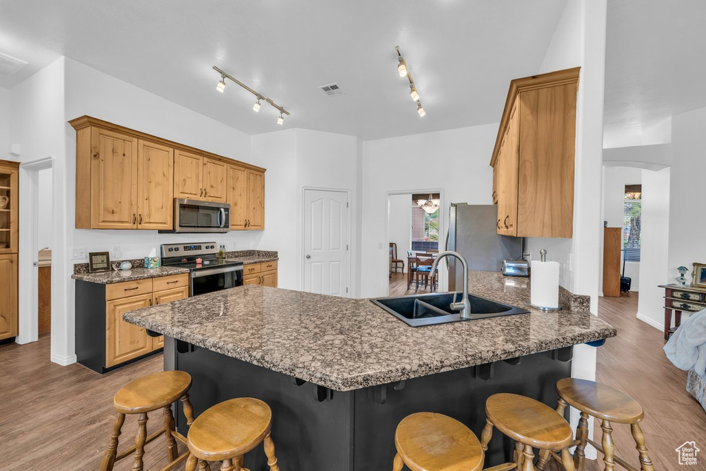 Kitchen featuring appliances with stainless steel finishes, a sink, a breakfast bar area, and a peninsula