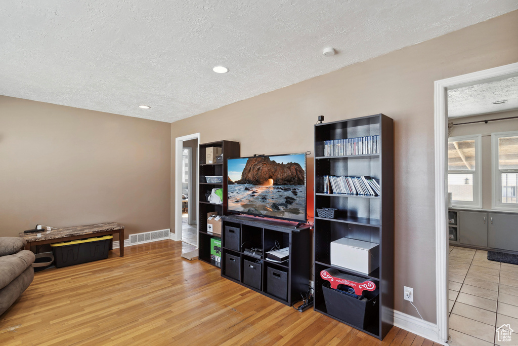 Living area featuring a textured ceiling, baseboards, and light wood-type flooring