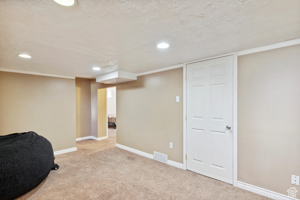 Finished below grade area with recessed lighting, carpet flooring, baseboards, and a textured ceiling