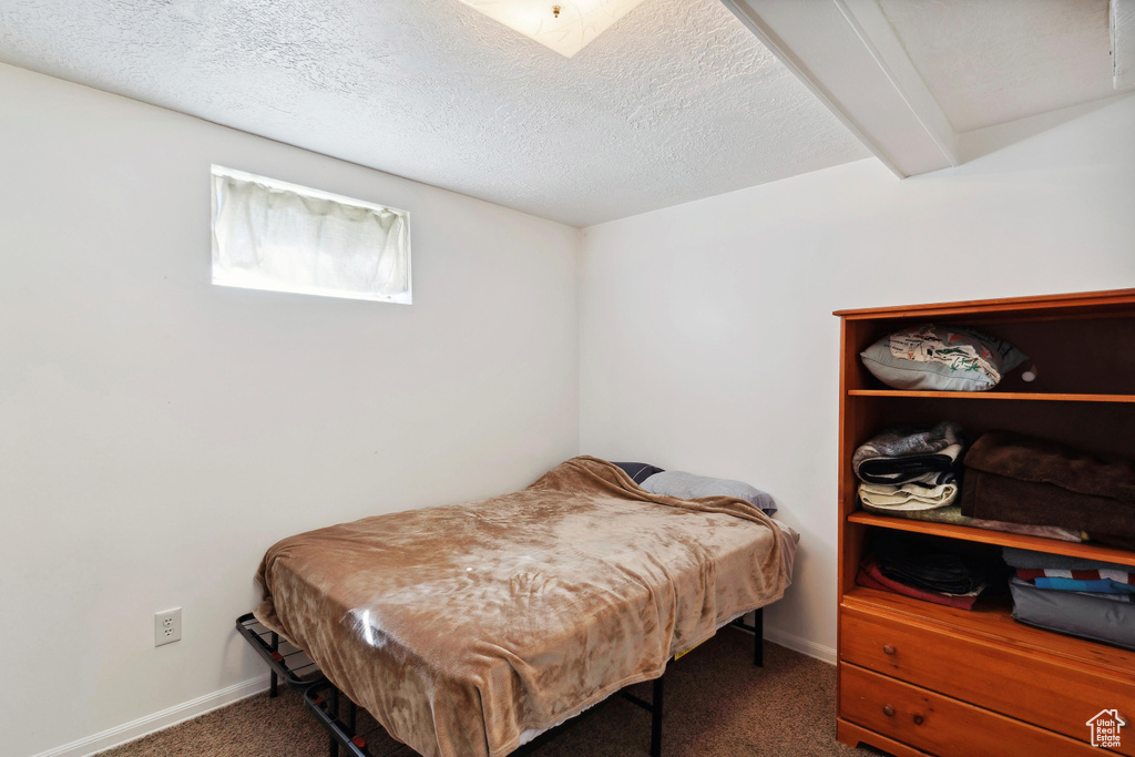 Bedroom with carpet flooring, baseboards, and a textured ceiling