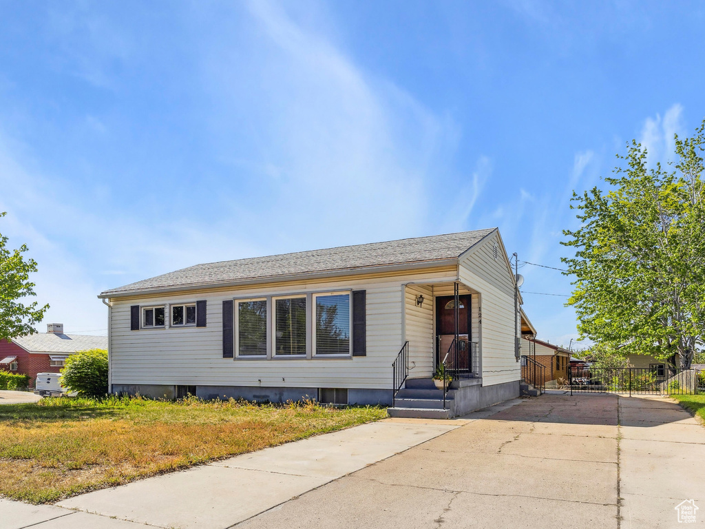 Bungalow featuring concrete driveway and a front yard
