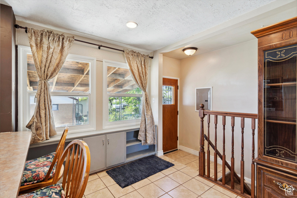 Entrance foyer with light tile patterned flooring, a textured ceiling, and baseboards