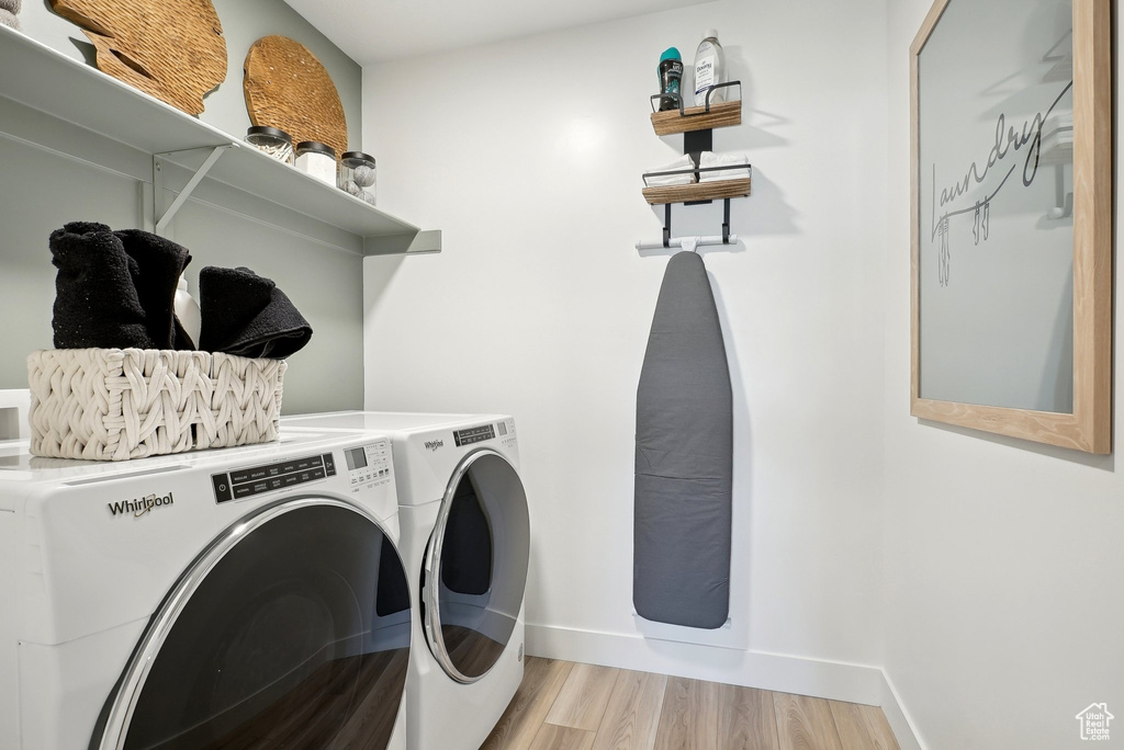 Laundry room featuring washer and dryer, light wood-style floors, and baseboards