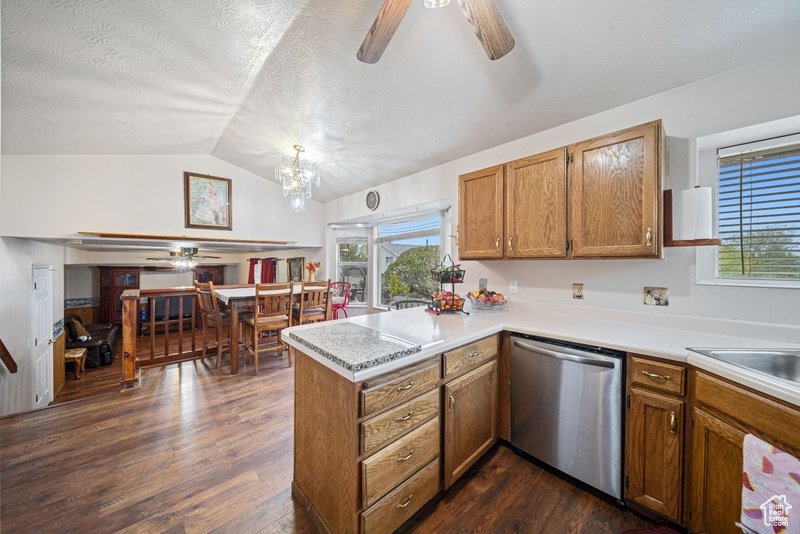 Kitchen featuring dishwasher, ceiling fan, a peninsula, brown cabinets, and lofted ceiling