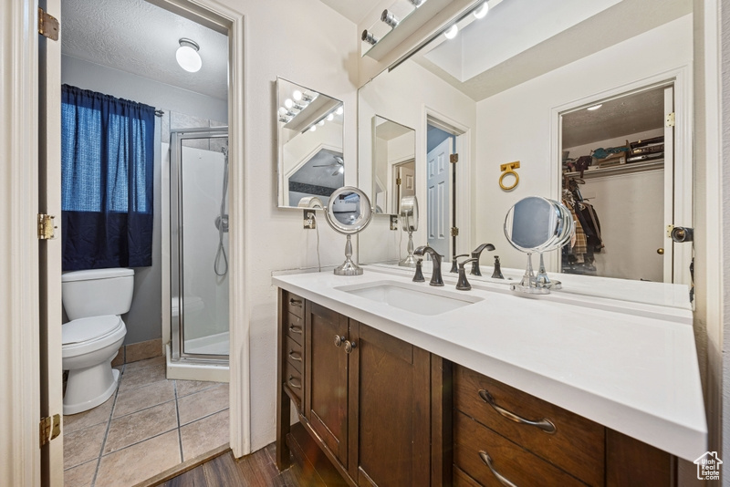 Full bath featuring toilet, a shower stall, vanity, and wood finished floors
