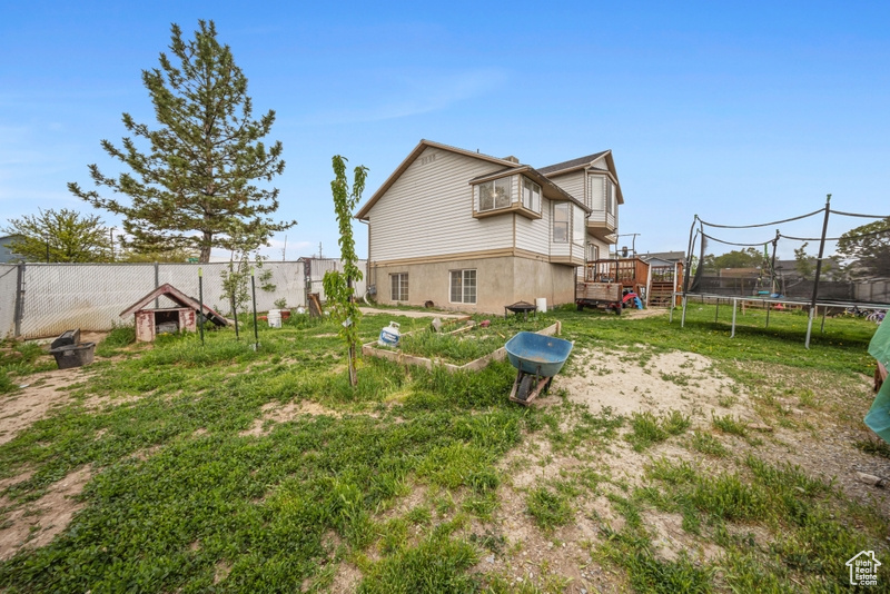 View of yard with a trampoline and a deck