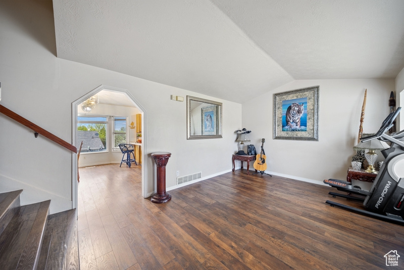 Exercise room with wood finished floors, lofted ceiling, baseboards, and arched walkways