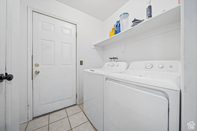Laundry room with separate washer and dryer and light tile patterned floors