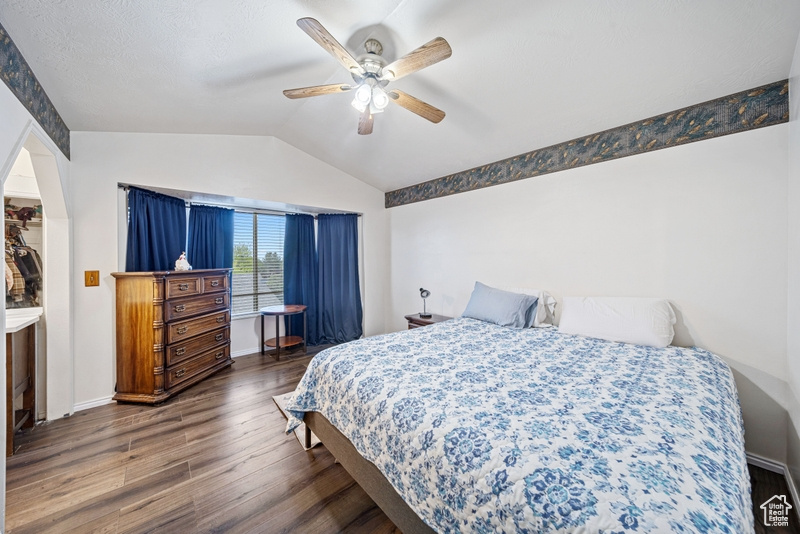 Bedroom with wood finished floors, vaulted ceiling, ceiling fan, and baseboards