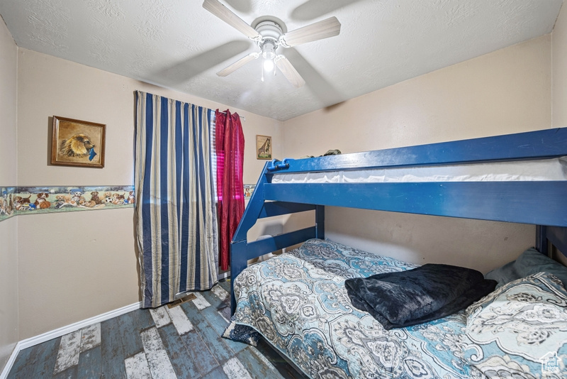 Bedroom featuring wood finished floors, baseboards, ceiling fan, and a textured ceiling