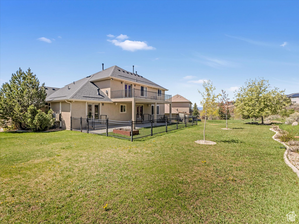 Back of house featuring a patio area, stucco siding, a balcony, and roof with shingles