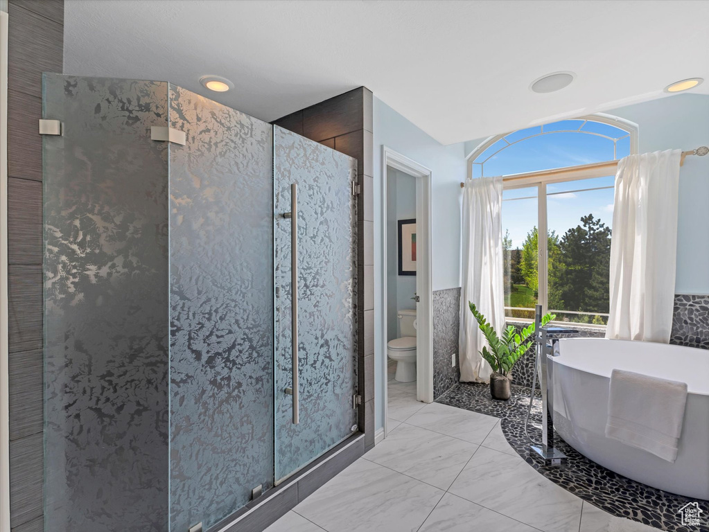 Full bathroom with a shower stall, toilet, and a soaking tub
