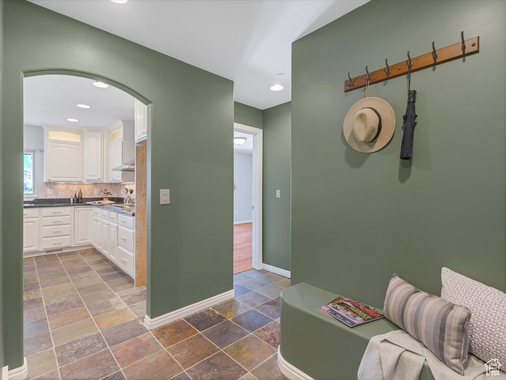 Corridor featuring stone tile floors, baseboards, recessed lighting, and arched walkways