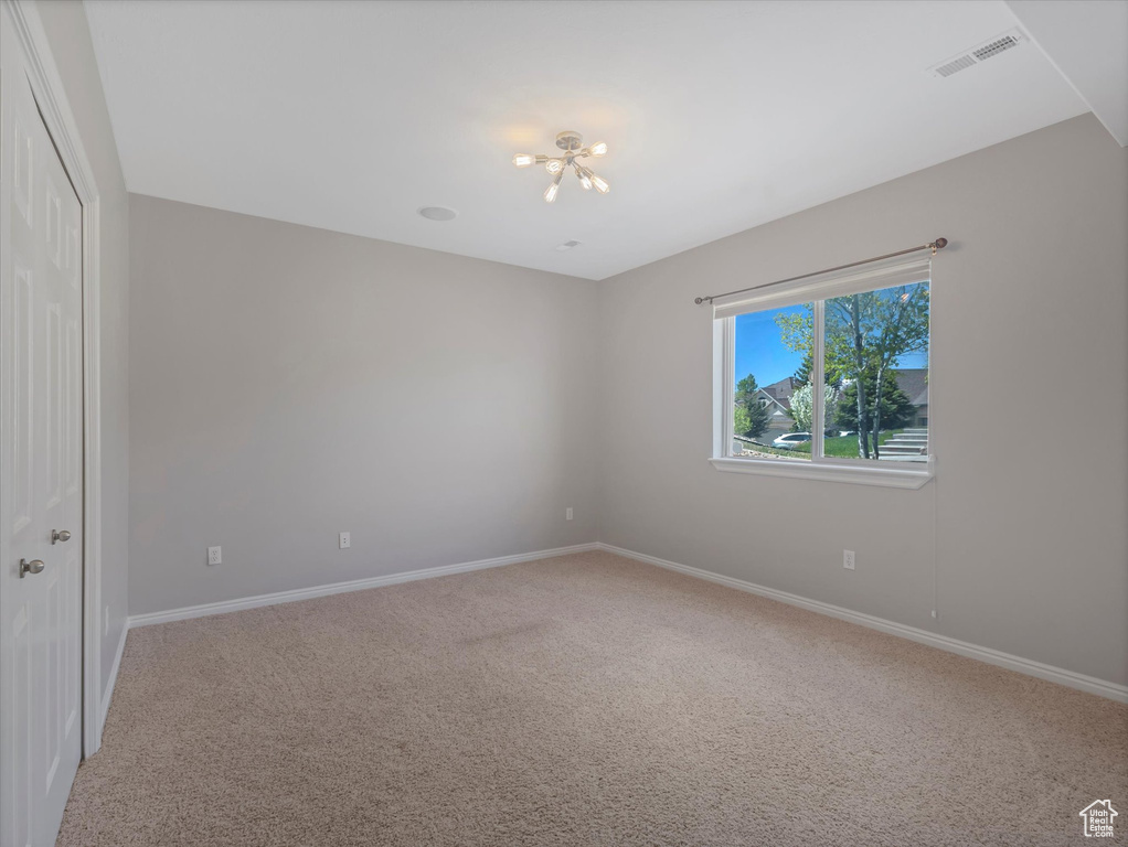 Unfurnished bedroom with a chandelier, light carpet, baseboards, and a closet