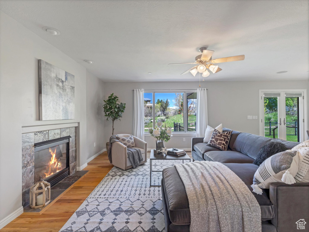 Living room featuring light wood-style floors, baseboards, a fireplace, and a ceiling fan