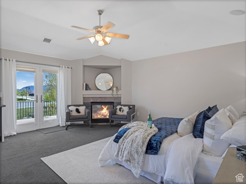 Bedroom with access to exterior, vaulted ceiling, carpet flooring, a tile fireplace, and ceiling fan