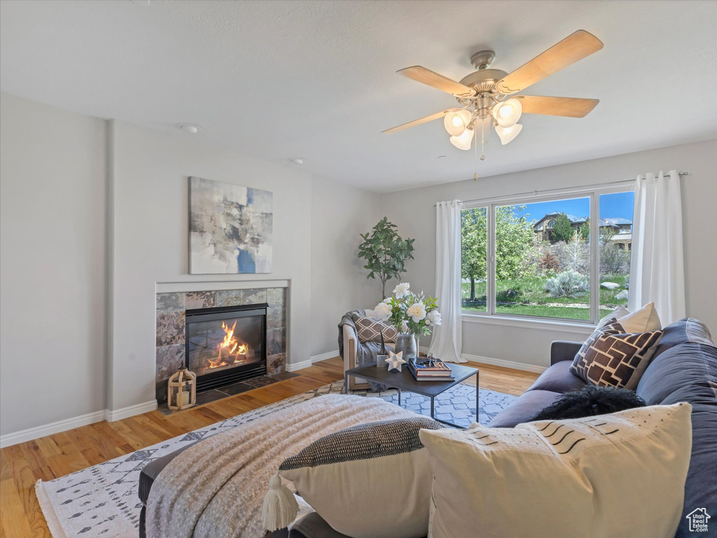 Living area with a tile fireplace, light wood finished floors, and baseboards