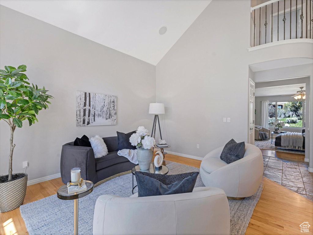 Living area with baseboards, high vaulted ceiling, wood finished floors, and ceiling fan