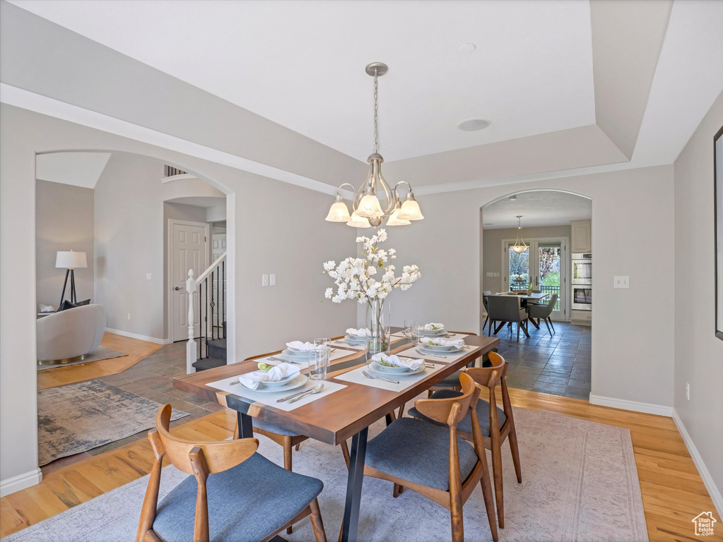 Dining room featuring arched walkways, a chandelier, stairway, and baseboards