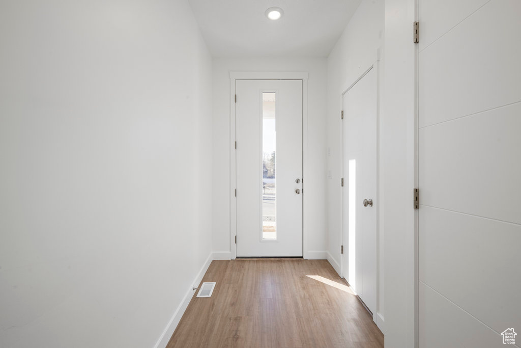 Doorway featuring light wood-type flooring, baseboards, and recessed lighting