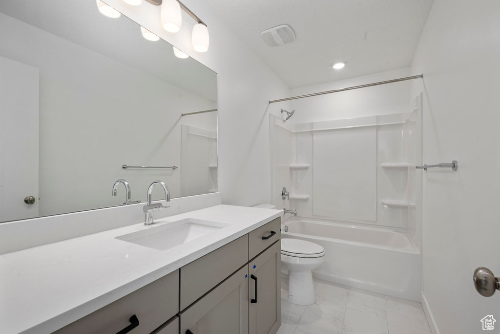 Bathroom with marble finish flooring, toilet, vanity,  shower combination, and baseboards