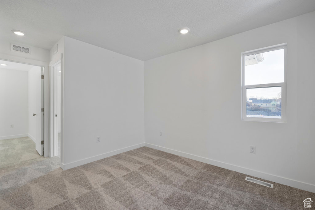 Unfurnished room with light carpet, baseboards, and recessed lighting
