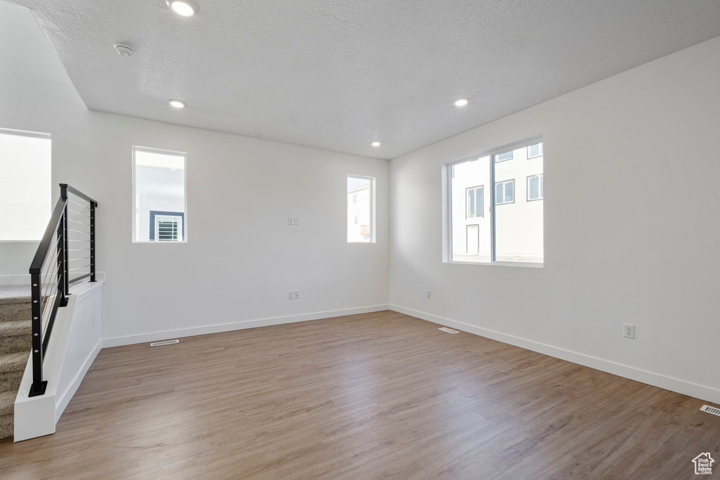 Spare room featuring stairway, light wood finished floors, baseboards, recessed lighting, and a smoke detector