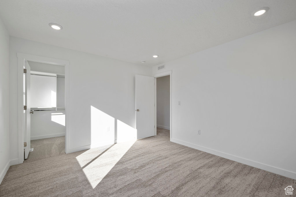 Unfurnished bedroom with carpet, a walk in closet, recessed lighting, baseboards, and a closet