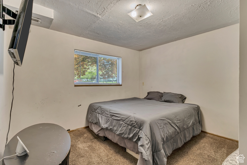 Carpeted bedroom featuring a textured ceiling and baseboards
