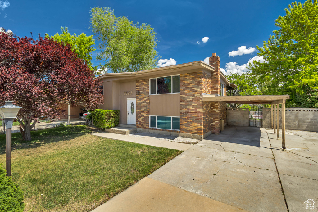 View of front of property with a chimney, brick siding, and driveway