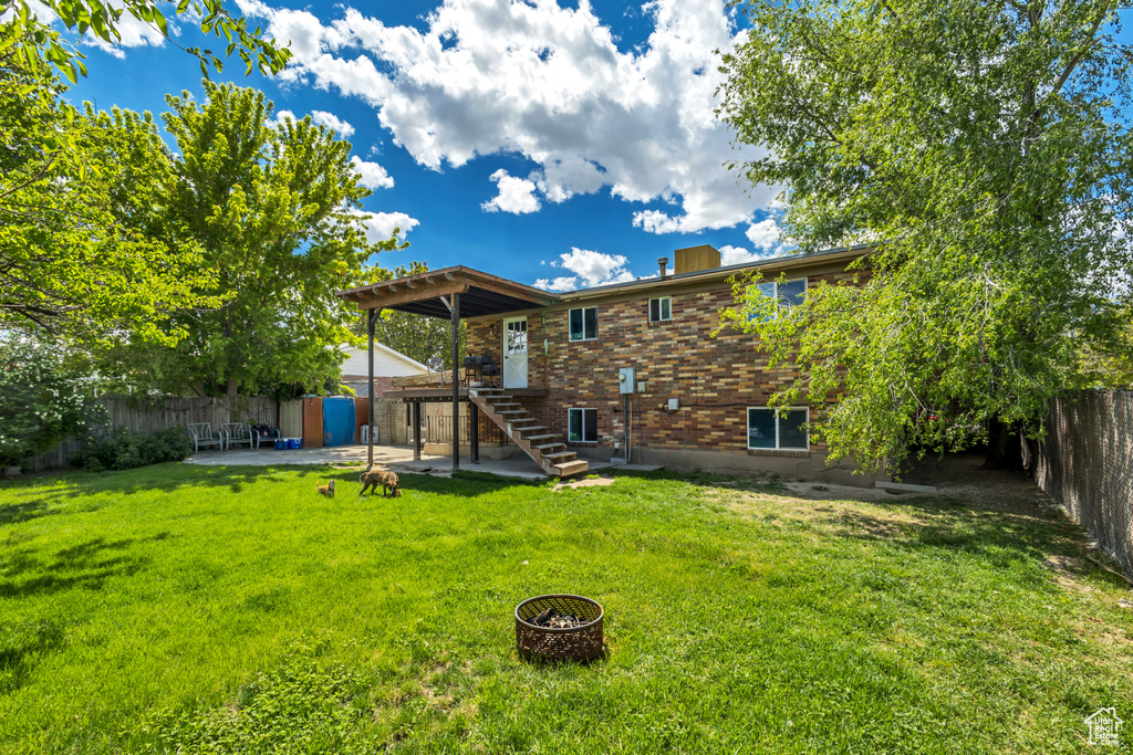 Rear view of property with stairs, a patio, brick siding, and an outdoor fire pit