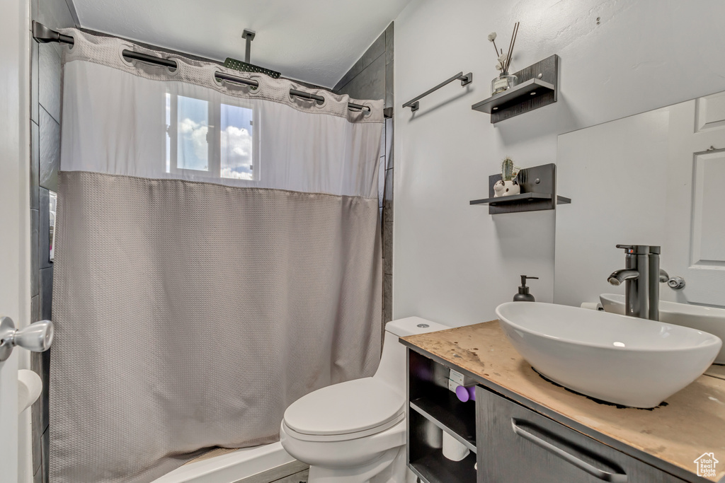 Bathroom featuring toilet, curtained shower, and vanity