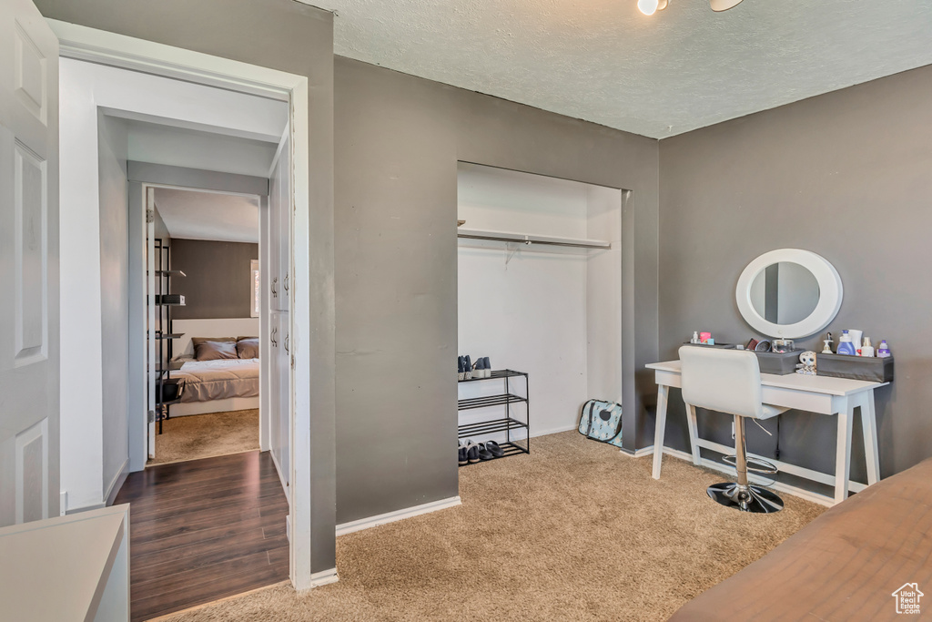 Carpeted office space featuring a textured ceiling and baseboards