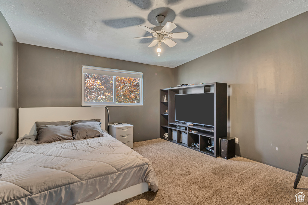 Carpeted bedroom featuring ceiling fan and a textured ceiling