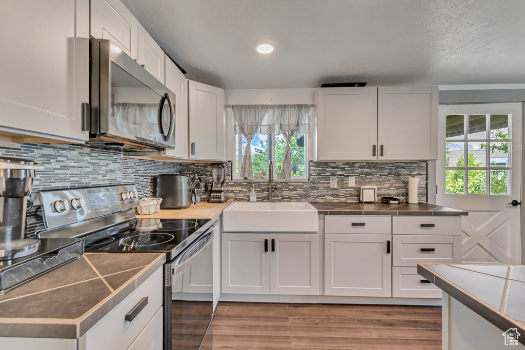 Kitchen featuring range with electric cooktop, stainless steel microwave, a sink, and healthy amount of natural light
