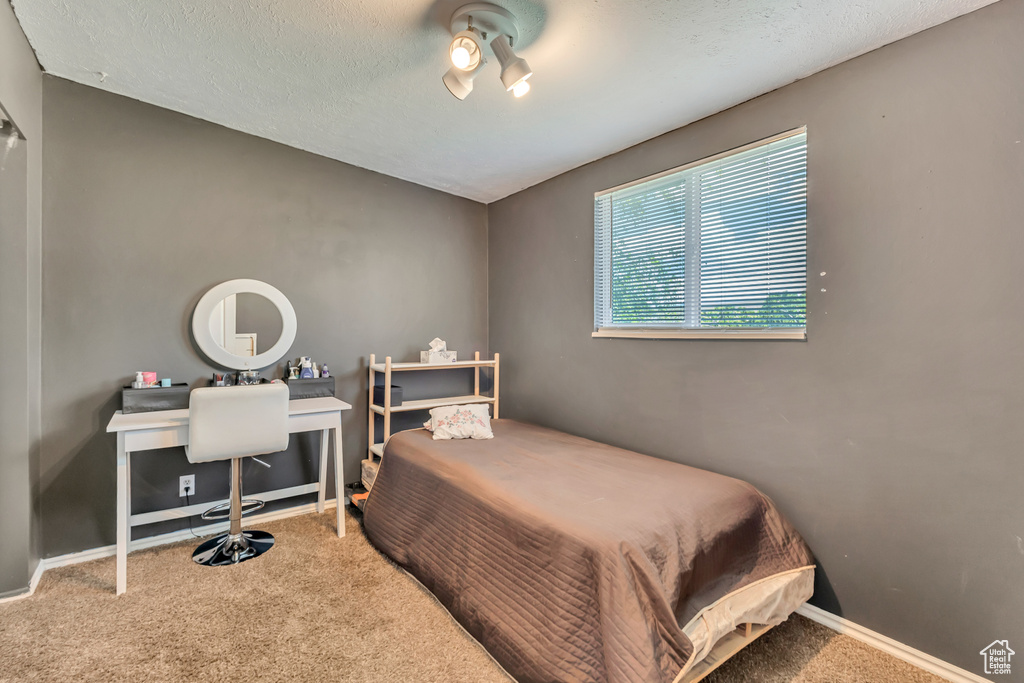 Carpeted bedroom with a textured ceiling and baseboards