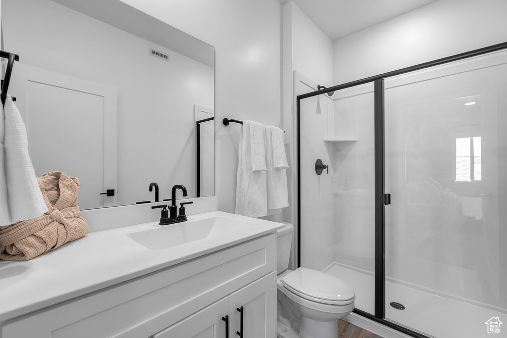 Full bath featuring a shower stall, toilet, vanity, and wood finished floors