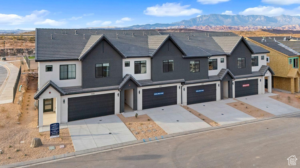 View of property with an attached garage, stucco siding, and a mountain view
