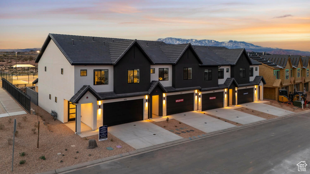 View of front of home featuring a garage, stucco siding, driveway, a mountain view, and fence