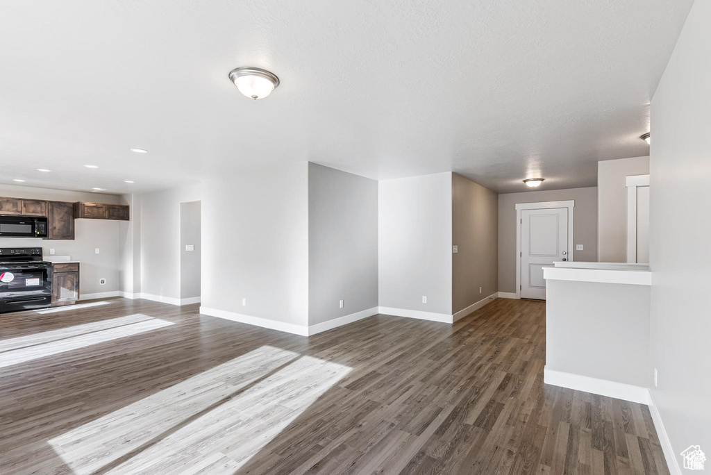 Unfurnished living room with baseboards, dark wood-style floors, and recessed lighting