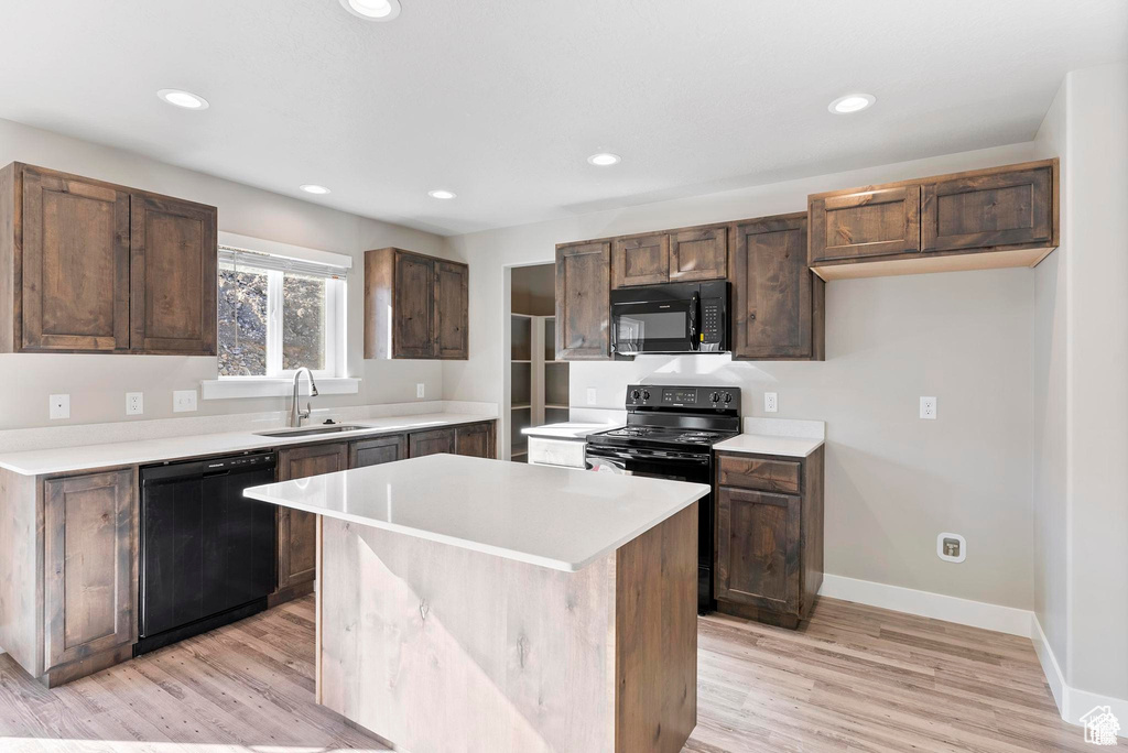 Kitchen featuring black appliances, a sink, light wood-style flooring, light countertops, and recessed lighting