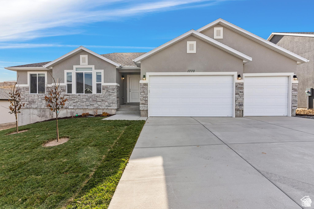 View of front facade featuring stone siding, stucco siding, a garage, and driveway