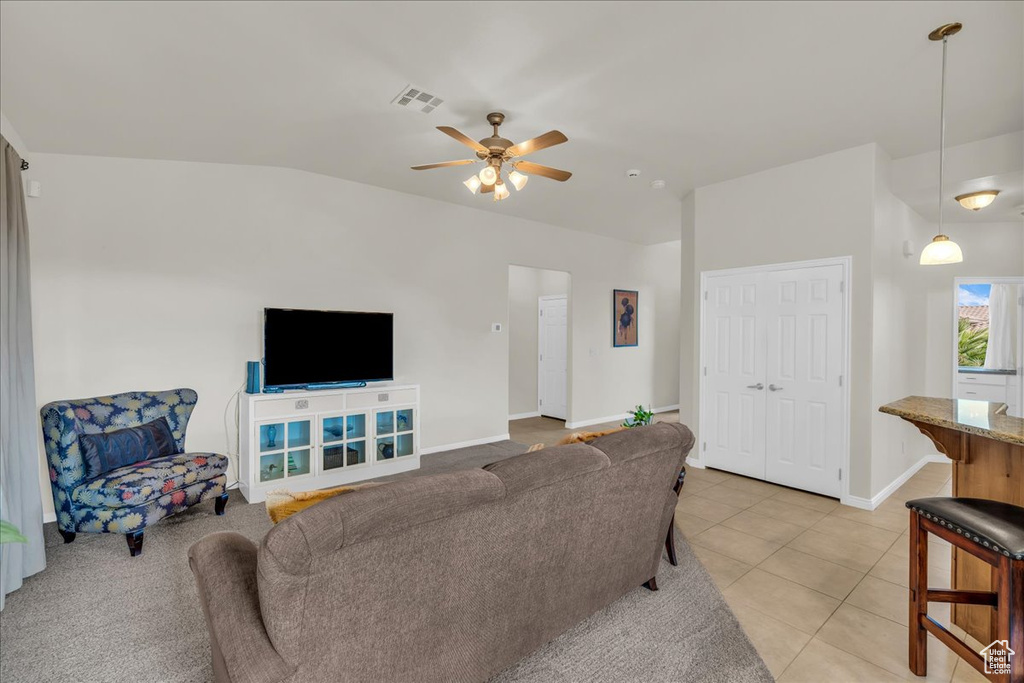 Living area with ceiling fan, light tile patterned floors, baseboards, and lofted ceiling