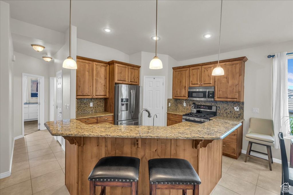 Kitchen featuring stainless steel appliances, brown cabinets, baseboards, and light tile patterned floors