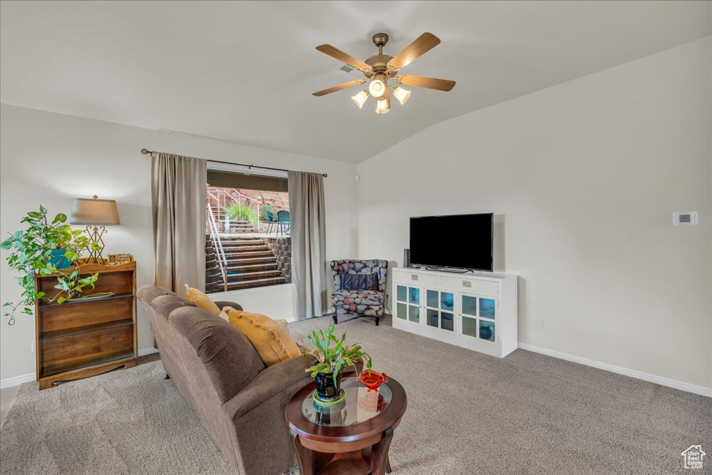 Carpeted living area featuring vaulted ceiling, a ceiling fan, and baseboards