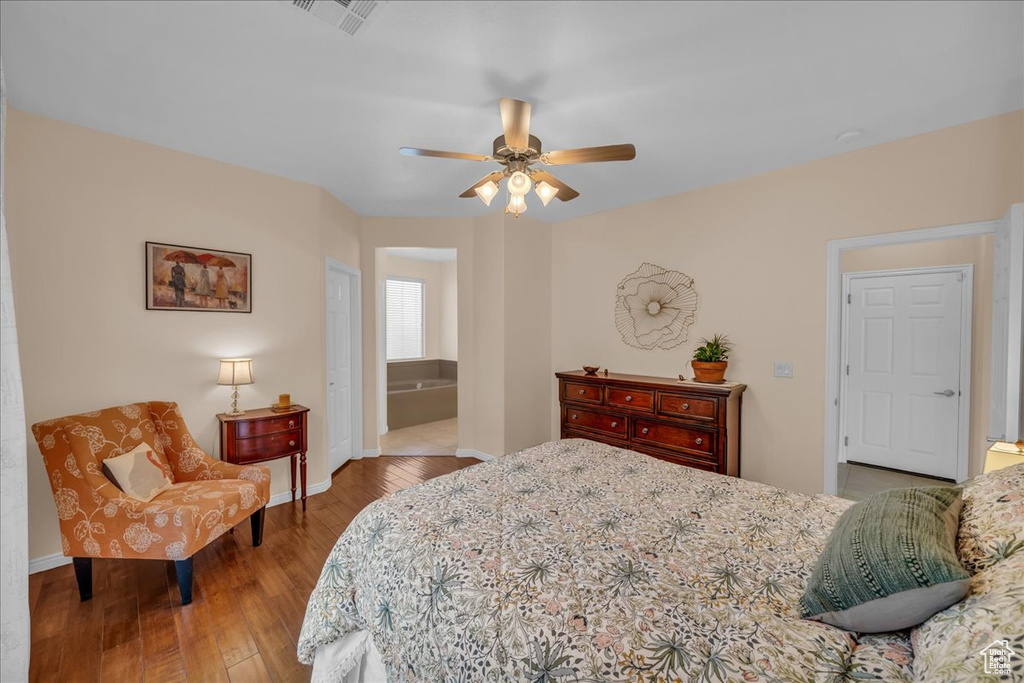 Bedroom featuring hardwood / wood-style floors, baseboards, ceiling fan, and connected bathroom