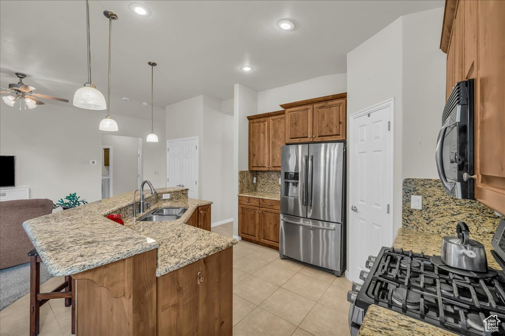 Kitchen with black appliances, a sink, open floor plan, brown cabinetry, and decorative backsplash