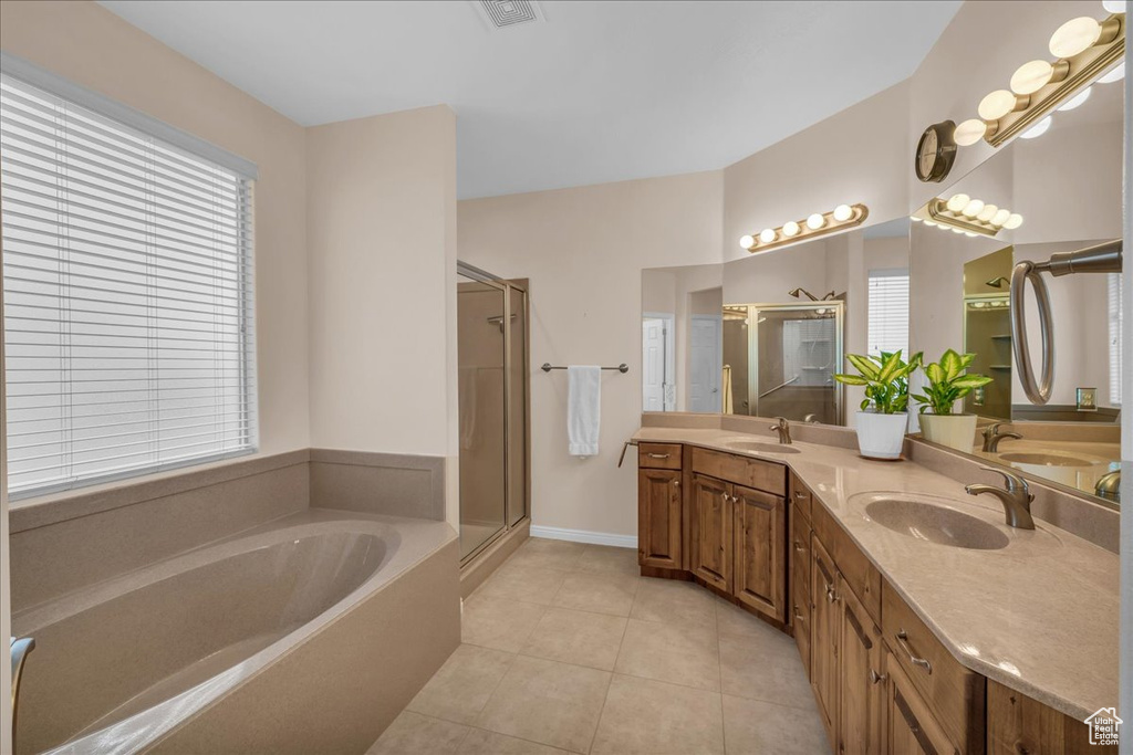 Bathroom featuring a garden tub, a shower stall, tile patterned floors, and double vanity
